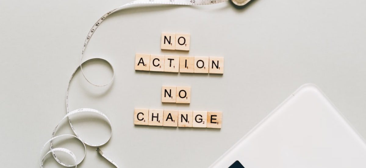 Motivational concept with scrabble tiles spelling no action no change alongside a measuring tape and scale.